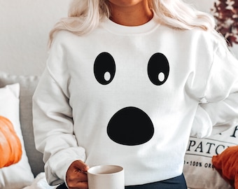 Può includere: Felpa bianca con un design a forma di volto di fantasma sorpreso, con grandi occhi e bocca neri. Questa felpa casual è ideale per Halloween o eventi a tema. Il design è semplice e audace.