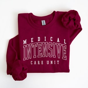 May include: Burgundy sweatshirt with white text that reads "MEDICAL INTENSIVE CARE UNIT".