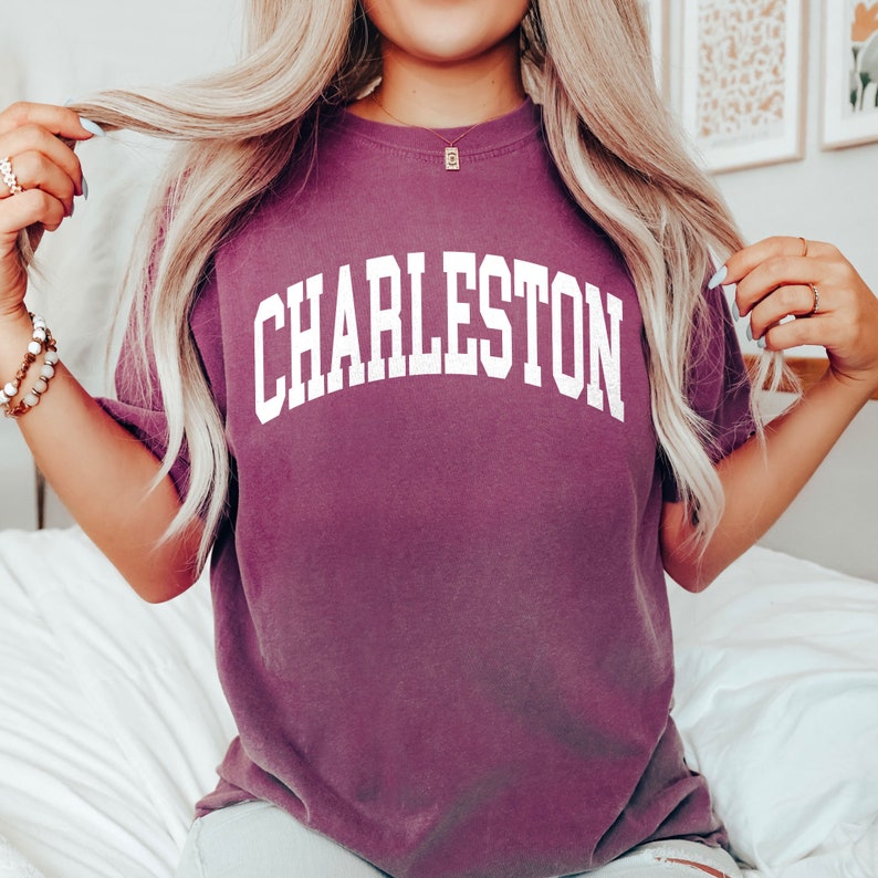 May include: A purple t-shirt with the word "CHARLESTON" printed in white on the front.