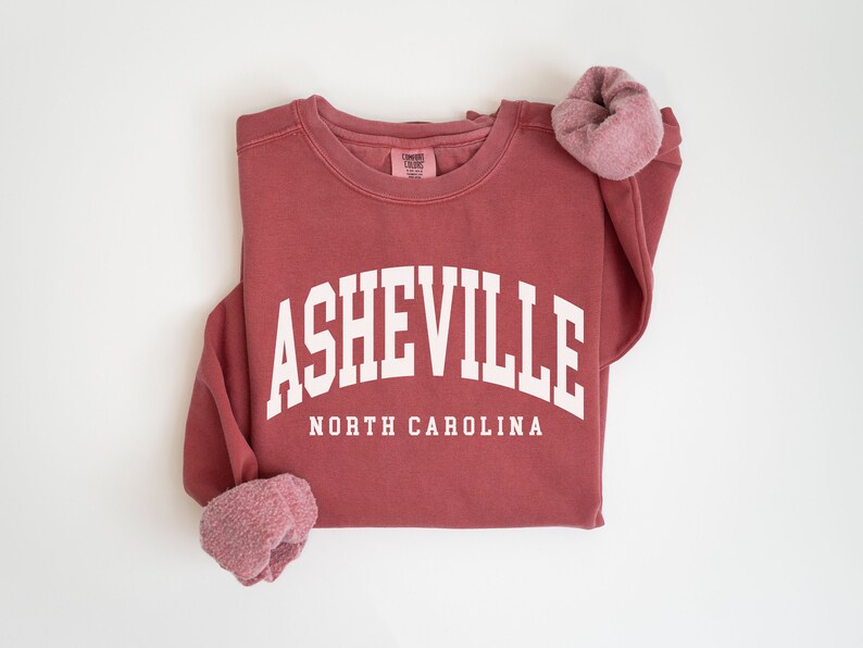 May include: A maroon sweatshirt with the text "ASHEVILLE NORTH CAROLINA" in white.