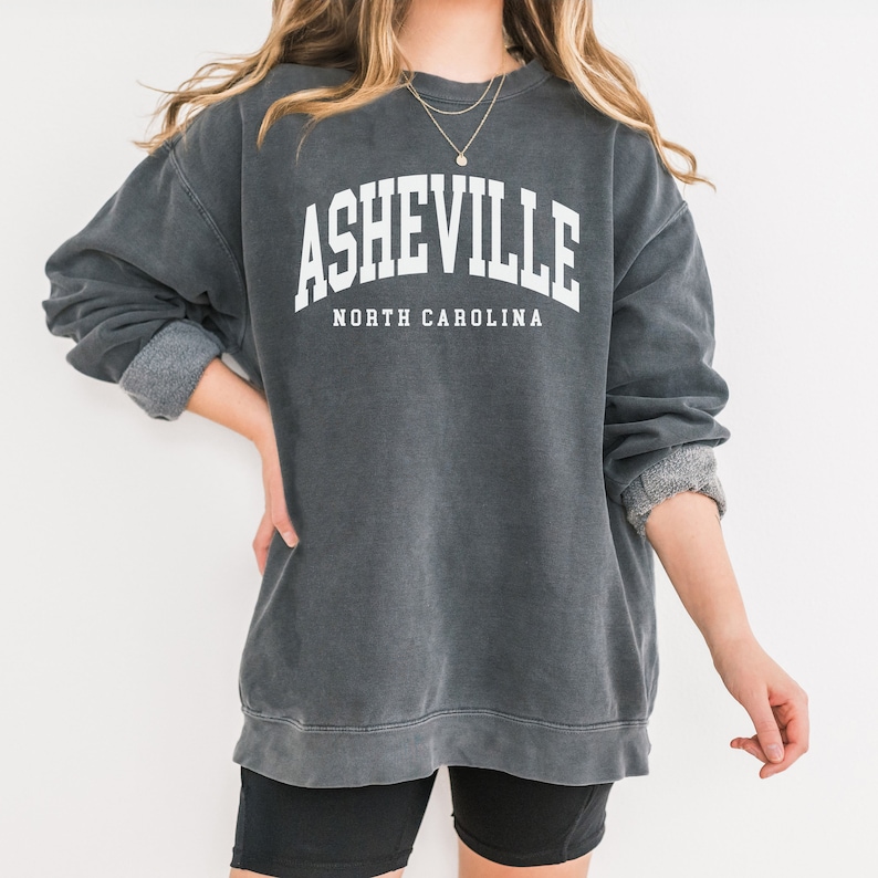 May include: A gray sweatshirt with the text "Asheville, North Carolina" printed in white.