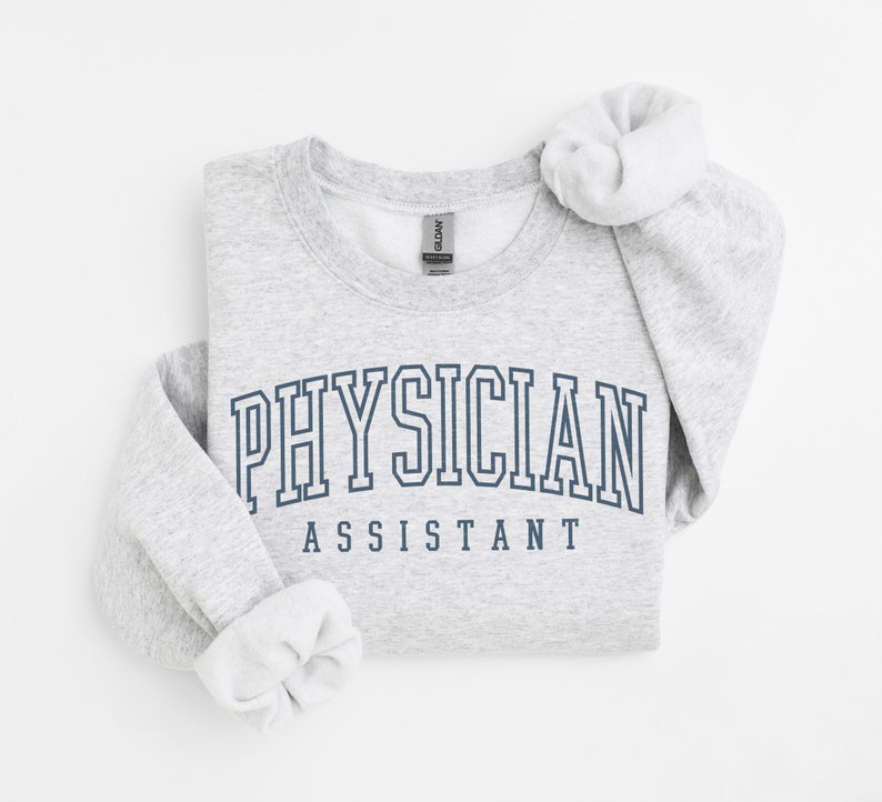 K&ouml;nnte beinhalten: Grauer Pullover mit dem Text "PHYSICIAN ASSISTANT" in dunkelblauer Schrift.
