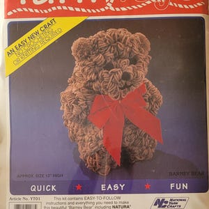 May include: A craft kit for making a yarn bear toy. The kit includes Natura Deluxe Acrylic Yarn, pom-poms, ribbon, and felt. The finished bear is approximately 12 inches tall. The packaging features the text "Yarn Toys" and "Barney Bear".
