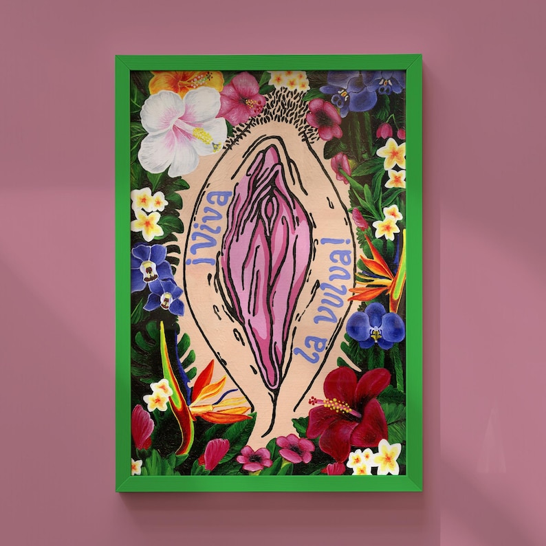 Vibrant Viva La Vulva art print featuring a pink vulva illustration surrounded by tropical flowers like hibiscus and birds of paradise, displayed in a bright green frame against a mauve wall.