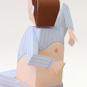 May include: A paper craft figure of a person with brown hair wearing a light blue and white pinstriped shirt that is lifted to reveal the torso. The figure has light skin, articulated arms, and is seated on a matching pinstriped surface.