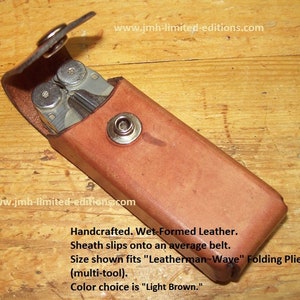 May include: A light brown leather sheath for a Leatherman Wave multi-tool. The sheath is handcrafted and wet-formed. It slips onto a belt. "Handcrafted. Wet-Formed Leather. Sheath slips onto an average belt. Size shown fits "Leatherman Wave" Folding Pliers (multi-tool). Color choice is "Light Brown."