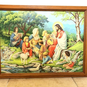Peut inclure: Une peinture encadr&eacute;e repr&eacute;sentant J&eacute;sus entour&eacute; d'enfants dans un paysage verdoyant luxuriant. La peinture repr&eacute;sente un ruisseau, un agneau et un canard. Les couleurs sont vives et vibrantes, avec des nuances de vert, bleu, rouge et jaune.