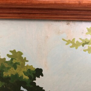 Peut inclure: Un gros plan sur une peinture repr&eacute;sentant un paysage avec des arbres verts et un ciel bleu clair. La peinture est encadr&eacute;e dans un cadre en bois.