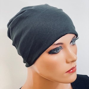Könnte beinhalten: Eine schwarze Mütze aus weichem Stoff. Die Mütze wird auf einem Mannequin-Kopf getragen.