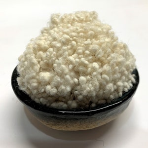 May include: A bowl filled with white fluffy yarn. The bowl is black with a brown rim.