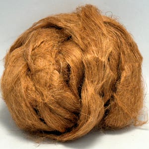 Könnte beinhalten: Nahaufnahme eines Knäuels brauner Fasern, wahrscheinlich natürlichen Ursprungs. Die Fasern sind dicht gepackt und bilden eine dichte, runde Form. Die Farbe ist ein warmes, erdiges Braun, was auf einen natürlichen Ursprung hindeutet. Das Bild ist gut beleuchtet.