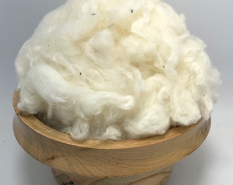May include: A white, fluffy pile of cotton fiber in a wooden bowl.