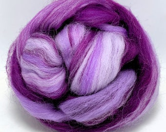 May include: A close-up of a ball of purple and white wool roving. The wool is soft and fluffy, and it is ideal for felting or spinning.