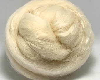 May include: A close-up of a ball of natural white wool fiber. The wool is soft and fluffy, and it is perfect for spinning or felting.