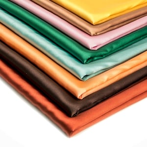 Peut inclure: Un ensemble de huit échantillons de tissu satiné de différentes couleurs. Les couleurs sont le brun, l'orange, l'orange clair, le bleu sarcelle, le vert, le rose, le brun et le jaune.