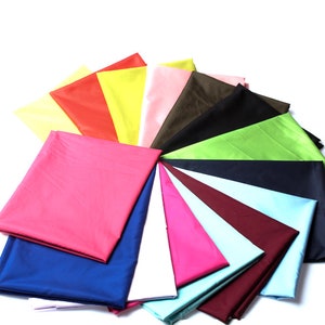 Peut inclure: Un éventail de 14 échantillons de tissu de différentes couleurs, dont le jaune, le rouge, le rose, le vert, le bleu et le marron. Les échantillons sont disposés en forme d'éventail.