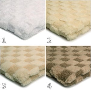 Pode incluir: Uma coleção de quatro cobertores dobrados com uma superfície de pelúcia texturizada. Os cobertores são exibidos em quatro variações de cores distintas: branco sólido, creme sólido, um padrão xadrez creme e bege, e um padrão xadrez bege e marrom.