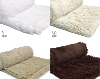 Peut inclure: Une collection de quatre couvertures en fausse fourrure présentées en différentes couleurs. Le numéro 1 est blanc éclatant, le 2 est crème, le 3 est beige clair et le 6 est marron foncé. Chaque couverture est pliée avec une partie étendue.