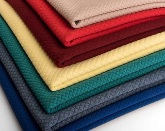 May include: A stack of fabric swatches in various colors, including beige, red, burgundy, yellow, teal, blue, and gray. The fabric has a quilted texture.
