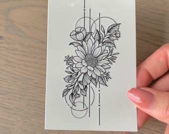 Puede incluir: Un tatuaje temporal en blanco y negro con un diseño floral con un girasol, hojas y formas geométricas.