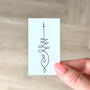 May include: A small white card with a black line drawing of a simple geometric design. The design is a vertical line with a series of loops and dots.