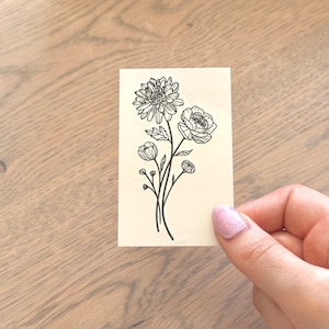 May include: A black and white line drawing of a bouquet of flowers. The bouquet includes a large flower with multiple petals, a smaller flower with five petals, and several buds.