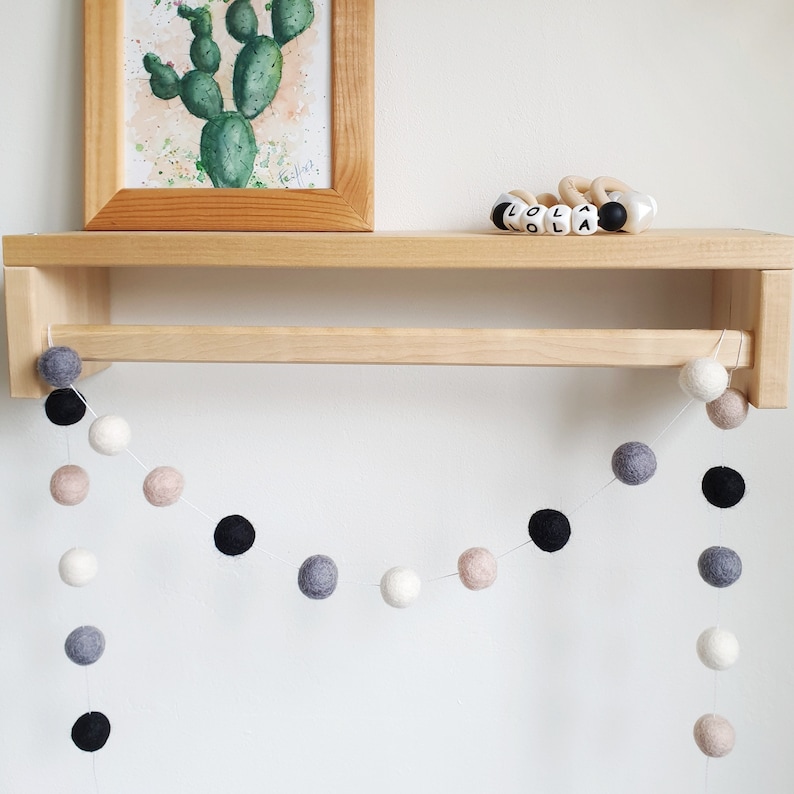 Pom Pom Felt Ball Garland shown hanging from a shelf, in Monochrome colours