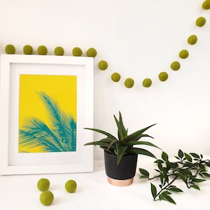 Pom Pom Felt Ball Garland shown hanging on a wall, in Lime colour