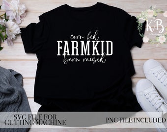 May include: Black t-shirt with white text that reads "corn fed FARMKID barn raised". The shirt is laying flat on a wooden surface with a gray sweater and white sneakers nearby.