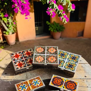 May include: Five rectangular and square boxes with metal frames and decorative ceramic tile lids. The tiles feature vibrant floral and geometric patterns in orange, blue, green, yellow, and white. The boxes are arranged on a wooden surface.