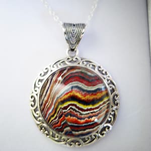 Puede incluir: Un collar de plata con un colgante de piedra de ágata de colores engastado en un marco de filigrana.