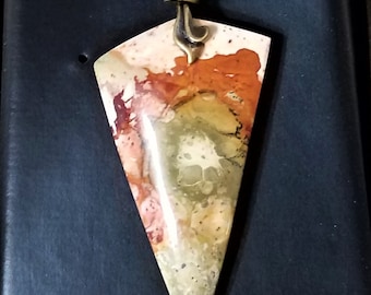 May include: A pendant necklace featuring a large, triangular, multi-coloured stone. The stone displays shades of brown, orange, yellow, and white. The pendant is attached to a brass chain.
