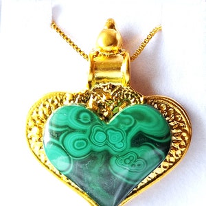 Puede incluir: Un colgante de corazón de oro con una piedra de malaquita verde. El colgante está en una cadena de oro.