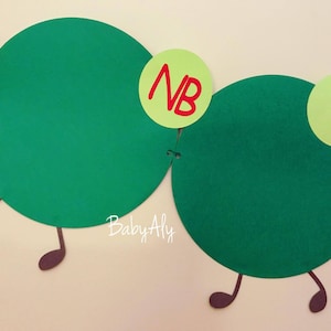 May include: Green felt circles with brown felt legs and red felt numbers on yellow felt circles. The numbers are "NB" and "1".