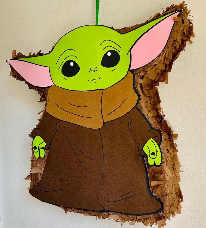 K&ouml;nnte beinhalten: Eine gr&uuml;ne und braune Pi&ntilde;ata in Form einer Figur aus dem Star Wars-Franchise. Die Figur hat gro&szlig;e Ohren, eine braune Robe und ein gr&uuml;nes Gesicht.