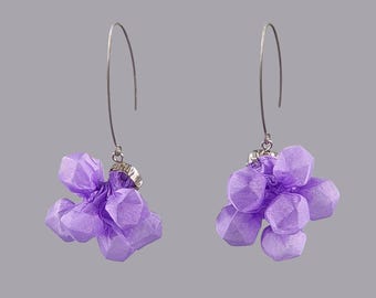 May include: A pair of drop earrings featuring clusters of light purple, faceted fabric beads attached to silver-toned metal hooks. Each earring consists of multiple small, geometric, semi-sheer purple fabric shapes gathered together at the top.