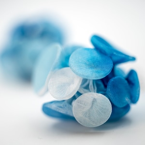 Puede incluir: Un grupo de círculos de tela azul y blanca, que se asemejan a una flor, con una superficie suave y texturizada.