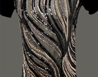 May include: A black short-sleeved shirt with a mock neck and a sheer panel in the front. The panel is decorated with gold and black sequins in a wavy pattern.