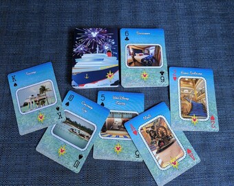May include: A deck of playing cards featuring images of a cruise ship and its various amenities, including a stateroom, a grand staircase, a pool, and a theater. The cards are designed with a nautical theme and feature a Mickey Mouse head logo.