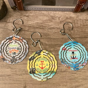 May include: Three metal wind spinners with different designs. The first is a Halloween themed spinner with the text "Bibbidi Bobbidi Boo" and a Mickey Mouse silhouette. The second is a yellow spinner with a Mickey Mouse silhouette and the text "I Want Adventure" and "Great Ride Forever". The third is a blue spinner with the text "H#OKED" and "Mickey Mouse Cruisin".