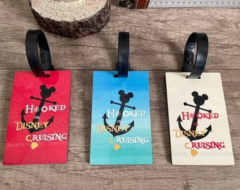 May include: Three luggage tags with black straps and Mickey Mouse anchors. The tags are red, blue, and white with the text "Hooked on Disney Cruising".