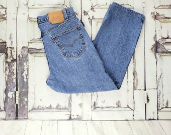May include: A pair of light blue denim jeans folded in half. The jeans have a brown leather patch on the back with the Levi's logo.