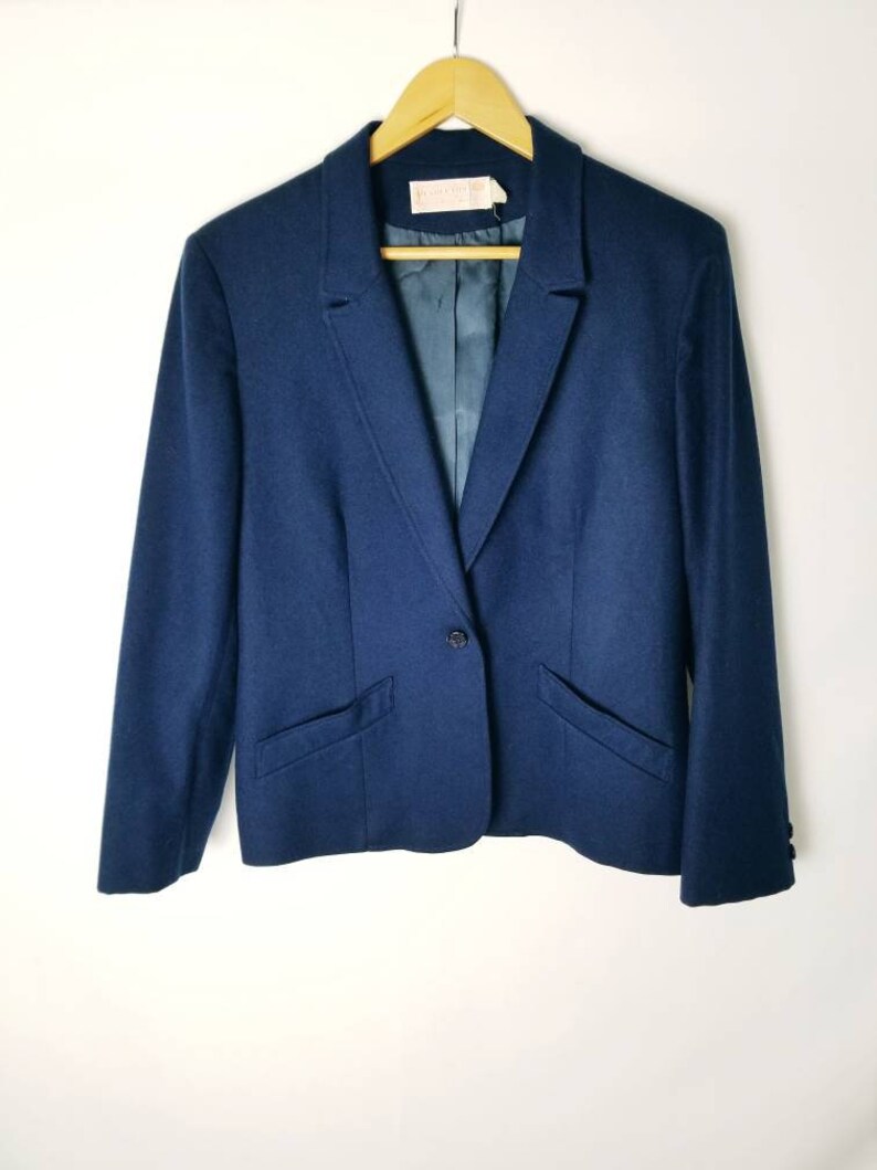 May include: A navy blue blazer with a single button closure and two pockets. The blazer has a classic style and is made of a soft, comfortable fabric.