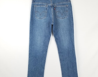 Puede incluir: Un par de pantalones vaqueros azules de mezclilla con un parche de cuero marrón en el bolsillo trasero. El parche tiene el logotipo de Levi's y el texto "Levi's" en blanco.