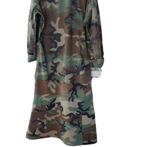 Pode incluir: Um casaco longo com padr&atilde;o de camuflagem. O casaco apresenta uma frente abotoada, mangas compridas e um colarinho. O design de camuflagem incorpora tons de verde, castanho e preto.