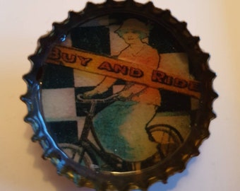 Buy and Ride. Cycle advert bottle top badge. Handmade recycled postcard badge.