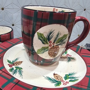 May include: Set of red and green plaid ceramic mugs and plates with a pine cone and holly design.