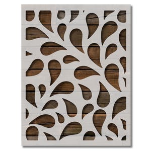 May include: A white stencil with a repeating pattern of teardrop shapes cut out. The stencil is placed on a background of brown wood planks.