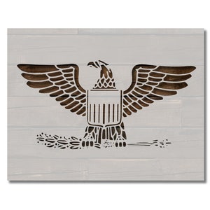 Könnte beinhalten: Wandkunst aus Holz mit einem detaillierten Adlerdesign. Der Adler mit ausgebreiteten Flügeln ist in Dunkelbraun geschnitzt und vor einem hellgrauen, holzgetäfelten Hintergrund platziert. Das Kunstwerk umfasst einen Schild und einen Olivenzweig.
