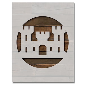 May include: A white castle silhouette cut out of a brown wood circle on a gray wood background.